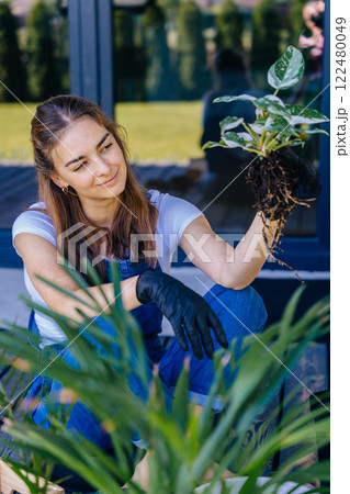 Vertical portrait of European female housewife enjoy working at terrace with plants at home. Leisure, lifestyle, mental health, real life concept. 122480049