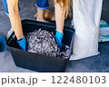 Unrecognizable housewife woman in gloves and casual home clothes preparing soil for plant transplantation in garage or utility room. Close up 122480103