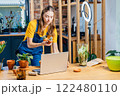 Self-employment. Online classes. Small business concept Professional young Asian female gardener making vlog session on plants pots arrangement class with laptop and phone camera at home. 122480110