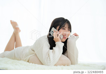 うつ伏せに寝て電話で話す日本人女性 122480493
