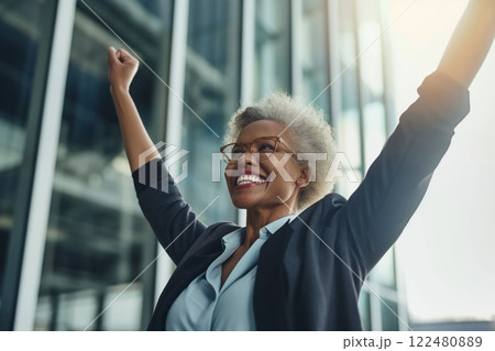 Triumphant and empowered female businesswoman celebrating her corporate success with joy and enthusiasm in a modern office building. Showcasing her achievement. Determination 122480889