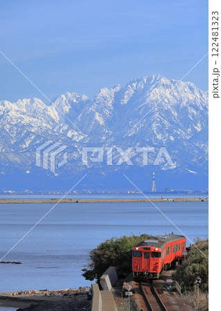 立山連峰をバックに雨晴海岸を走る氷見線列車 122481323