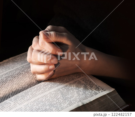 Hands clasped in prayer near an open book Hands clasped in prayer near an open book 122482157