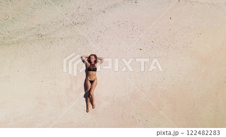 Woman sunbathes on a maldives beach, surrounded by turquoise waters and clear skies, capturing a moment of relaxation and tranquility Woman sunbathes on a maldives beach, surrounded by turquoise waters and clear skies, capturing a moment of relaxation and tranquility 122482283
