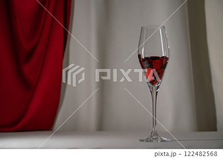 Wine glass with heart confetti on cream and red silk background. Minimalist lowkey holiday photo for Valentines 122482568