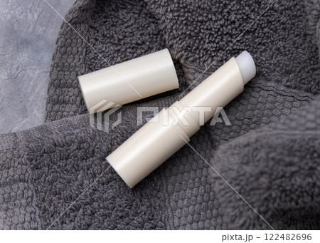 Opened lip balm stick near dark grey towel with blank lid, cosmetic mockup, lipcare product 122482696