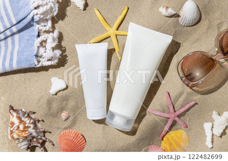Sunscreen cream tubes, starfishes and seashells on a sand top view, hand shadow, cosmetic mockup 122482699
