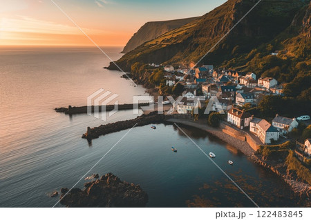 Aerial view of a picturesque coastal town at sunrise with a warm glow and tranquil morning light. Boats on the sea. Waterfront houses. And scenic landscape 122483845
