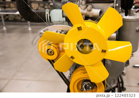 Close Up of Industrial Engine featuring a prominent Yellow cooling Fan and Pulley Mechanism. Mechanical components and design details and Craftsmanship, automotive Repair, Auto Industry themes Close Up of Industrial Engine featuring a prominent Yellow cooling Fan and Pulley Mechanism. Mechanical components and design details and Craftsmanship, automotive Repair, Auto Industry themes 122485323