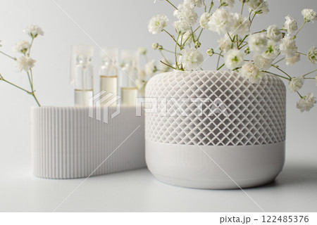 A small artificial plant with vibrant green leaves sits in a textured white pot against a clean white background 122485376