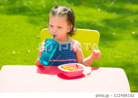 Toddler kid girl drinking eating pasta in garden 122486182