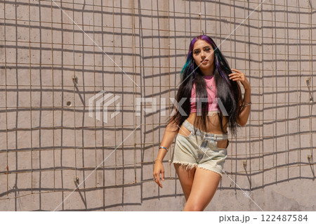 Beautiful cute smiling black hair latin woman in summer hipster casual clothes posing near wall 122487584