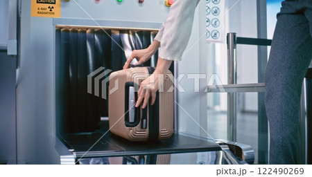 Security Checkpoint in Airport: Woman Takes Suitcase from Conveyor Belt after Baggage Screening 122490269