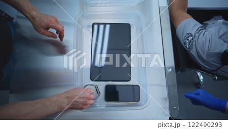 Top View on Passengers Placing Personal Items in Plastic Tray for Screening before Boarding Flight Top View on Passengers Placing Personal Items in Plastic Tray for Screening before Boarding Flight 122490293