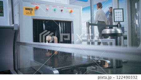 Passenger Places Suitcase on Conveyor Belt for Luggage Screening Passenger Places Suitcase on Conveyor Belt for Luggage Screening 122490332