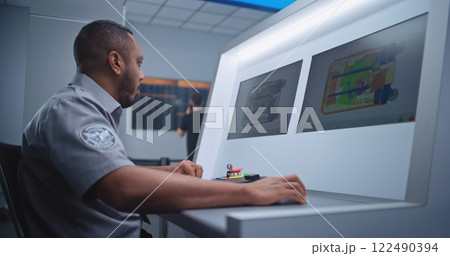 Airport Security Checkpoint: Security Officer Monitors Baggage Screening on Computer Screens Airport Security Checkpoint: Security Officer Monitors Baggage Screening on Computer Screens 122490394
