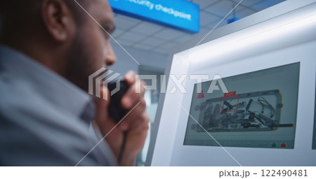 Airport Terminal: Security Officer Monitors X-ray Luggage Scanning on Screens, Finds Suspicious Item Airport Terminal: Security Officer Monitors X-ray Luggage Scanning on Screens, Finds Suspicious Item 122490481