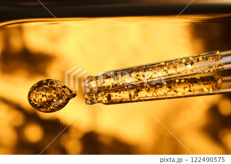 24 k gold facial serum in a pipette on a gold background. 24 k gold facial serum in a pipette on a gold background. 122490575
