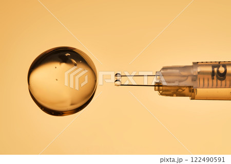 A drop of gel pours from a syringe for cosmetic procedures. 122490591