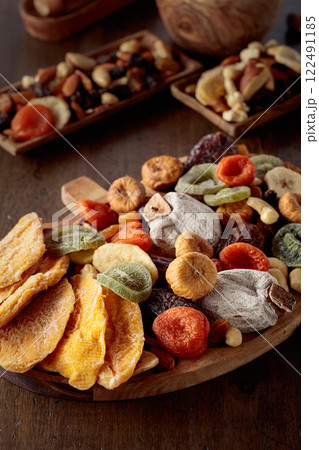 Dried mango slices, tropical fruits, nuts, and raisins on a wooden table. Dried mango slices, tropical fruits, nuts, and raisins on a wooden table. 122491185