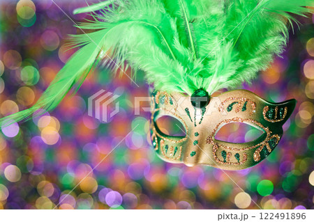 Festive Masquerade. A vibrant carnival mask with green feathers against a colorful, bokeh background. Festive Masquerade. A vibrant carnival mask with green feathers against a colorful, bokeh background. 122491896