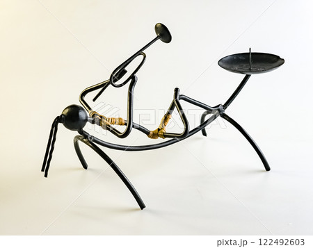 Candlestick made of black wire in the shape of a woman playing a trumpet on a white background Candlestick made of black wire in the shape of a woman playing a trumpet on a white background 122492603