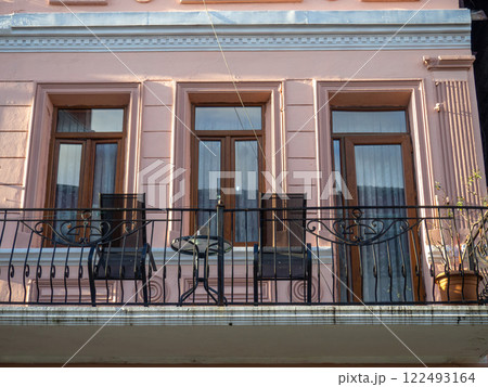 Building's facade. Balcony with chairs and a table on it. 122493164