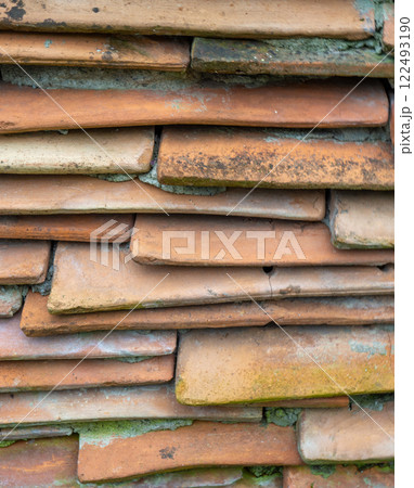 Background from the old tiled masonry. Orange tiles. Wall made of clay fragments. 122493190