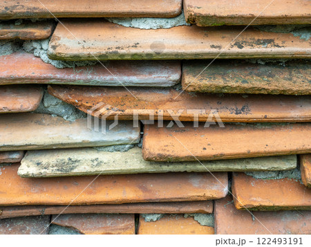 Background from the old tiled masonry. Orange tiles. Wall made of clay fragments. Wall texture. 122493191