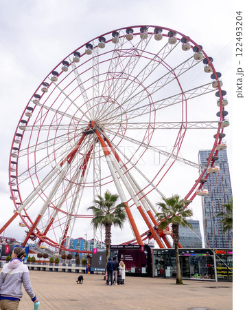 Ferris wheel on a cloudy day. Cloudy sky. Ferris wheel in an amusement park. Winter in the Black Sea resort. Batumi. Ferris wheel on a cloudy day. Cloudy sky. Ferris wheel in an amusement park. Winter in the Black Sea resort. Batumi. 122493204