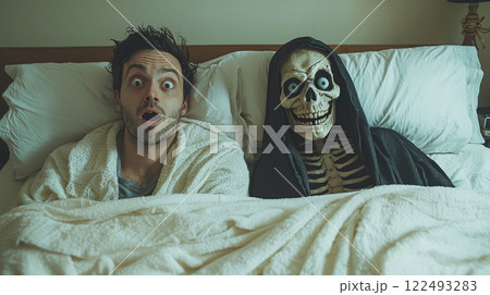 Man surprised in bed with skeleton in hoodie, shocked expression and humorous situation in bedroom at night 122493283