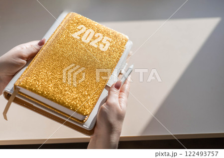 Gold colored diary, pen on bright background. New year planning concept. Minimalistic workstation. 122493757