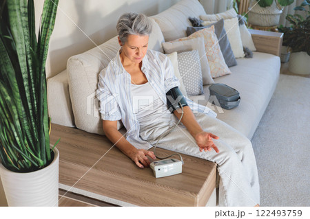 Concept health. An elderly beautiful gray-haired woman measures blood pressure 122493759