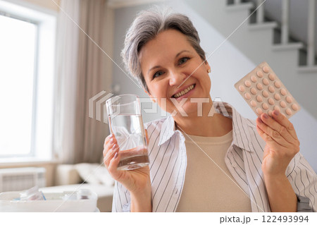 Beautiful elderly woman pensioner with gray hair is going to take a pill for a headache, painkiller Beautiful elderly woman pensioner with gray hair is going to take a pill for a headache, painkiller 122493994