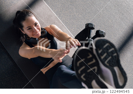 Beautiful athletic Asian woman trains in gymnastics studio, enjoys flexibility, well-being 122494545