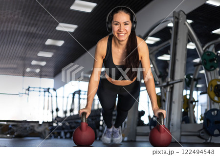 Young beautiful asian woman doing push ups with weights in gym 122494548