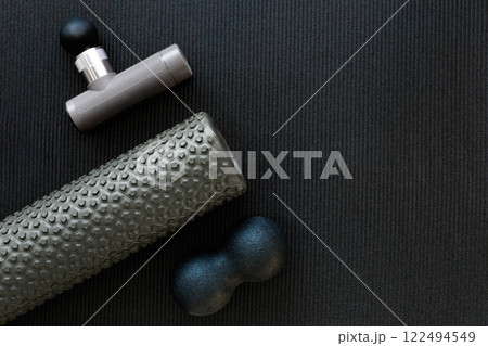 Sports massagers manual and electric in the gym on a black mat, flat layout.  122494549