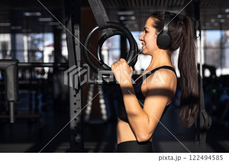 Young beautiful asian woman doing pull ups on rings in gym Young beautiful asian woman doing pull ups on rings in gym 122494585
