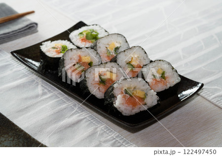Homemade salmon salad sushi on black plate with white placemat on table. Japanese healthy food. Selective focus. 122497450