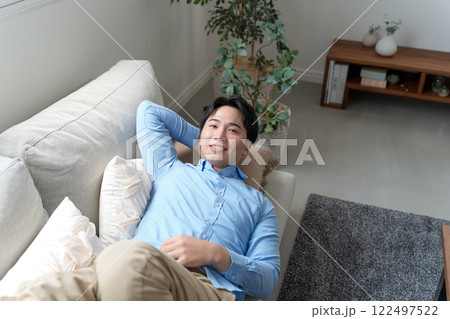 リビングのソファに寝そべる男性 122497522