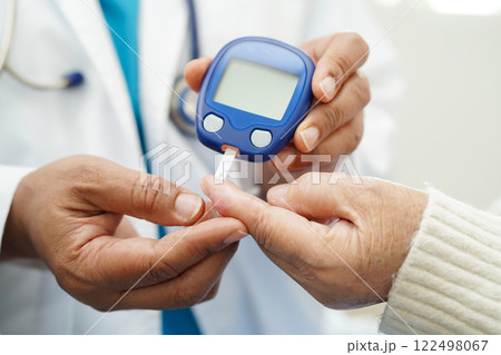 Asian doctor using digital glucose meter for check sample blood sugar level to treatment diabetes. Asian doctor using digital glucose meter for check sample blood sugar level to treatment diabetes. 122498067