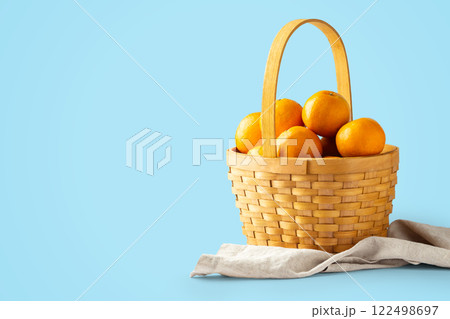 Oranges fruit in woven basket on linen fabric on blue background 122498697