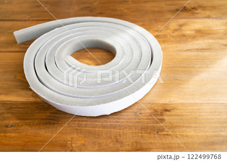 木目の上に置かれたすきまテープ、クローズアップ 122499768