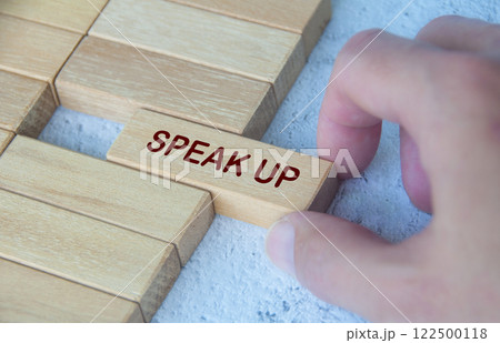 Hand pulling wooden block with text SPEAK UP. Courage concept Hand pulling wooden block with text SPEAK UP. Courage concept 122500118