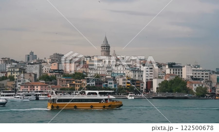 Scenic View of Istanbul's Galata Tower and Cityscape from the Water with a Yellow Passenger Ferry Boat Scenic View of Istanbul's Galata Tower and Cityscape from the Water with a Yellow Passenger Ferry Boat 122500678
