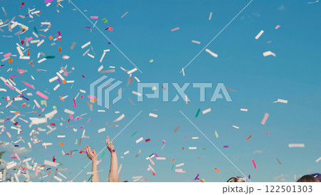 High school graduates joyfully tossing vibrant confetti into the air on a sunny summer day 122501303