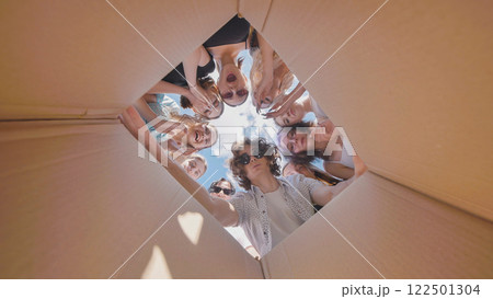 Happy high school students discovering a fun summer surprise inside a large cardboard box 122501304