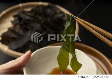 生わかめをしゃぶしゃぶで食べる　箸で生わかめを持ち上げる 122501538