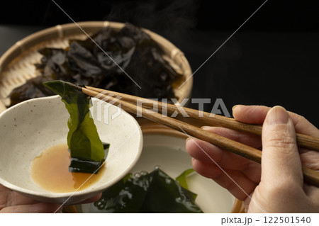生わかめをしゃぶしゃぶで食べる　箸で生わかめを持ち上げる 122501540