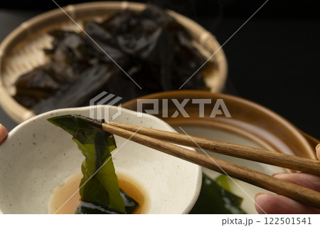 生わかめをしゃぶしゃぶで食べる　箸で生わかめを持ち上げる 122501541